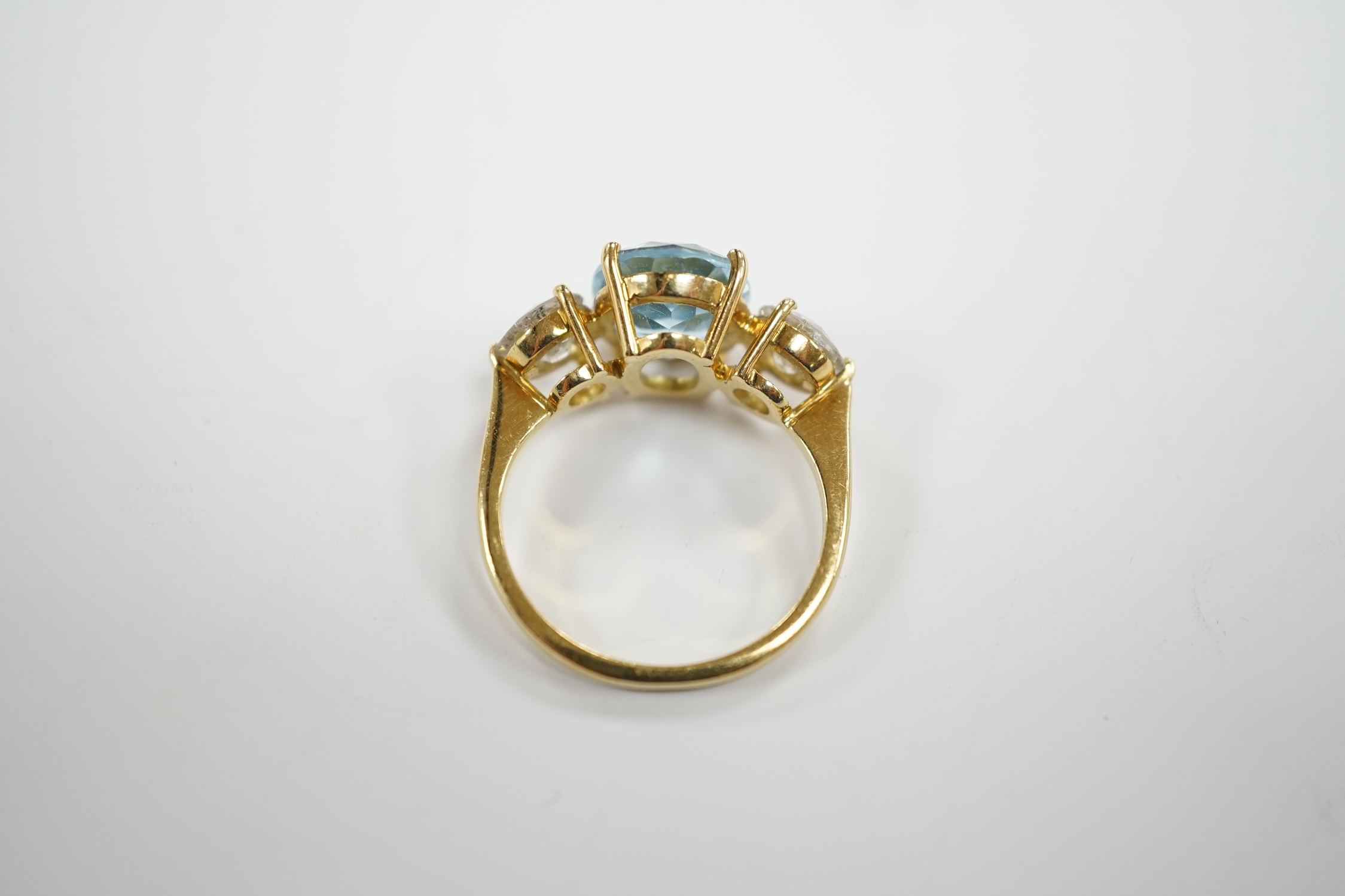 A modern 18ct gold, single stone oval cut aquamarine and two stone round brilliant cut diamond set ring, size L, gross weight 4.8 grams.